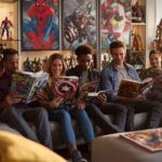 Modern oturma odasında Marvel çizgi romanları okuyan ve süper kahraman filmleri izleyen çeşitli insanlar, koleksiyon figürleri ve Marvel posterleriyle.