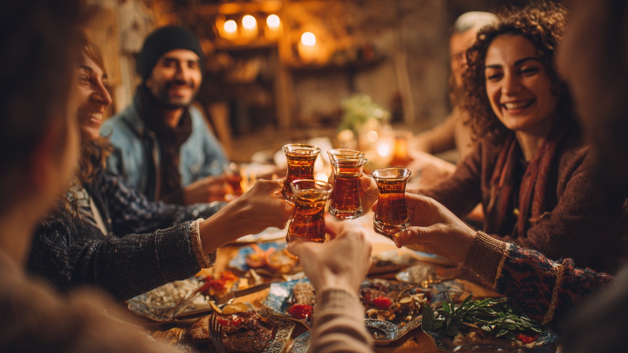 Samimi bir Türk rakı sofrasında arkadaşlar meze ve rakı bardaklarıyla sohbet ederken, sıcak ve davetkar atmosfer.